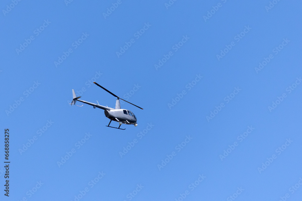 A gray helicopter crosses the blue sky with clouds. Transportation. Urban. A gray helicopter crosses the blue sky with clouds. Transportation. Urban.