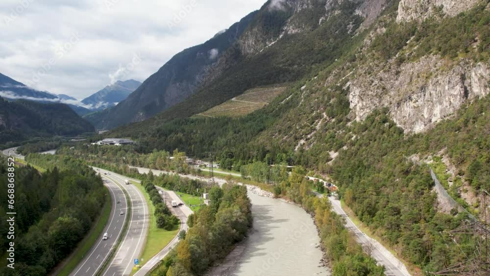 Aerial view of highway interstate road with fast moving traffic near big river in Alps mountains Aerial view of highway interstate road with fast moving traffic near big river in Alps mountains