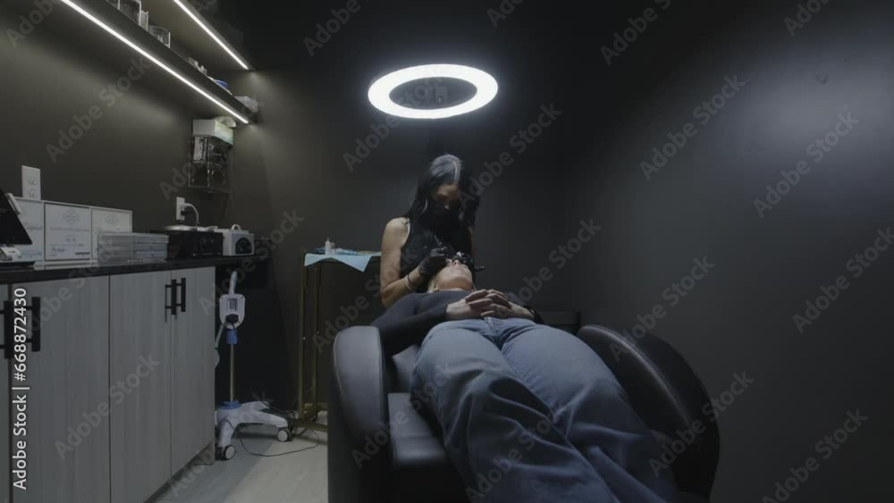 Cosmetician applying permanent tattoo to eyebrow of customer / Cedar Hills, Utah, United States Cosmetician applying permanent tattoo to eyebrow of customer / Cedar Hills, Utah, United States