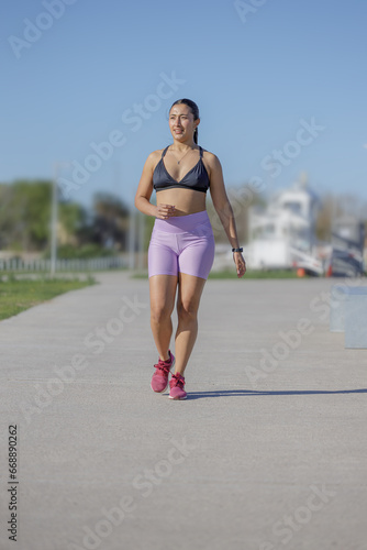 Latin girl in sportswear training in a public park.