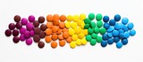 Round chocolate chips in rainbow colors melting on a white background to form chocolate shapes
