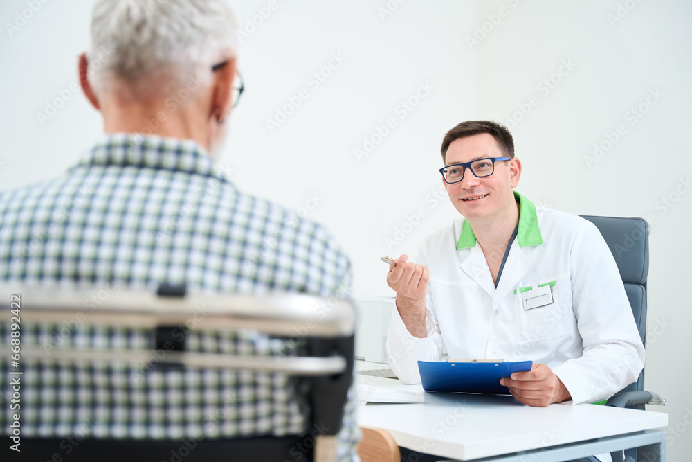 Man in a medical gown communicates with an old man