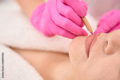 Marking a woman lips before a tattoo procedure