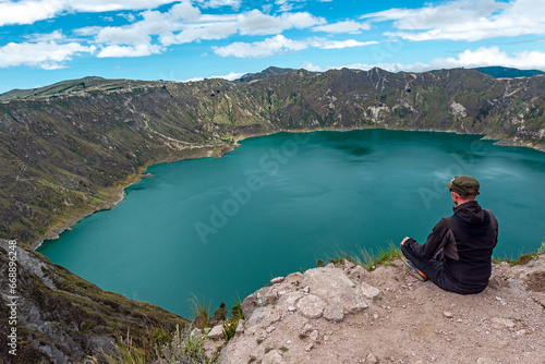 Male tourist hiker looking over Quilotoa Lake along the Quilotoa Lagoon Loop, Andes Mountains, Quito region, Ecuador. photo