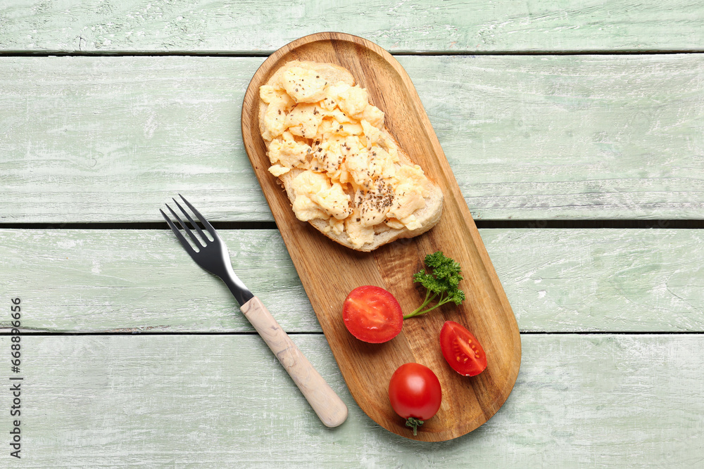 Plate with scrambled eggs sandwich and tomatoes on green wooden background Plate with scrambled eggs sandwich and tomatoes on green wooden background