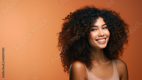 Beautiful girl smiling with curly hair and clean healthy skin on an orange background with copy space
