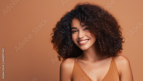 Beautiful girl smiling with curly hair and clean healthy skin on an orange background with copy space