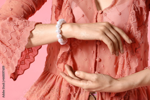 Stylish woman with pearl bracelet on pink background, closeup