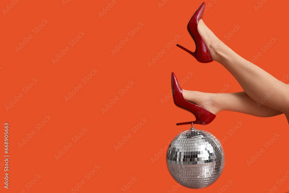 Female legs in stylish high heels with disco ball on red background - obrazy, fototapety, plakaty 