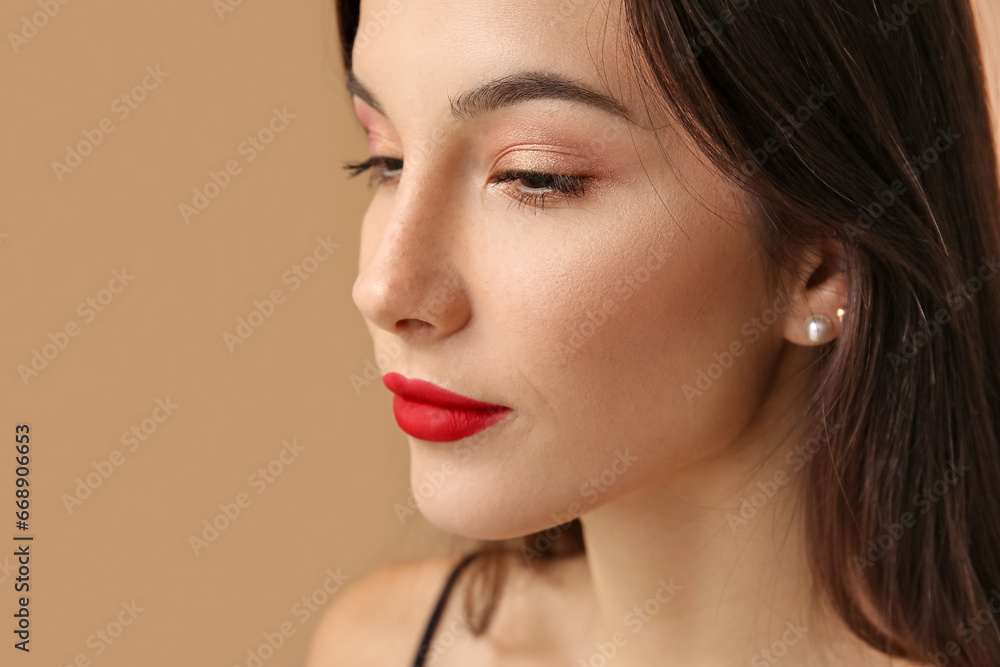 Fototapeta premium Beautiful young woman with eyeshadows on brown background