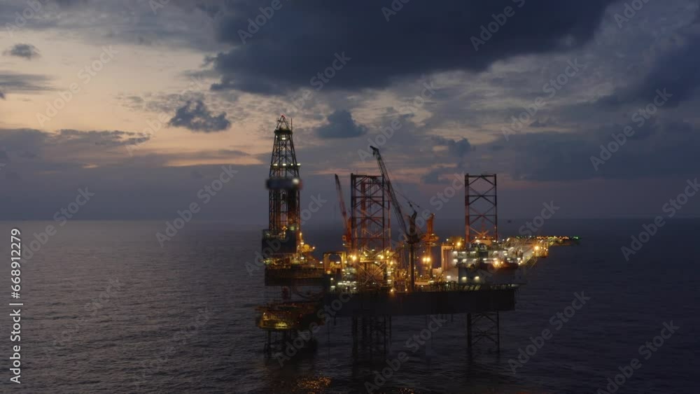 Aerial view of offshore jack up drilling rig during early night time - oil and gas industry Aerial view of offshore jack up drilling rig during early night time - oil and gas industry