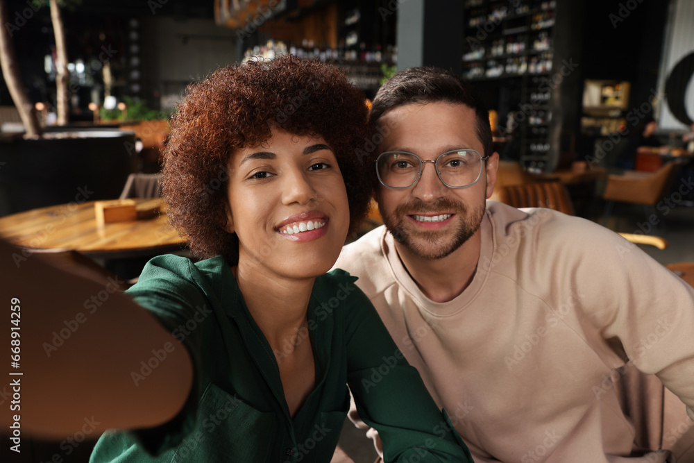 Fototapeta premium International dating. Happy couple taking selfie in cafe