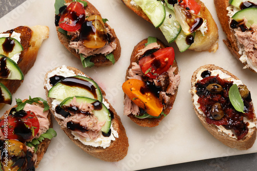 Delicious bruschettas with balsamic vinegar and different toppings on grey table, top view