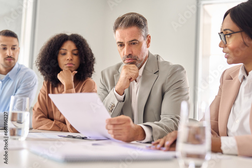Quadro em tela Serious senior Latin business man investor checking bank document at office team meeting with financial law experts lawyers attorneys team thinking of risks