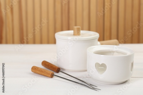Fondue set on white wooden table, space for text
