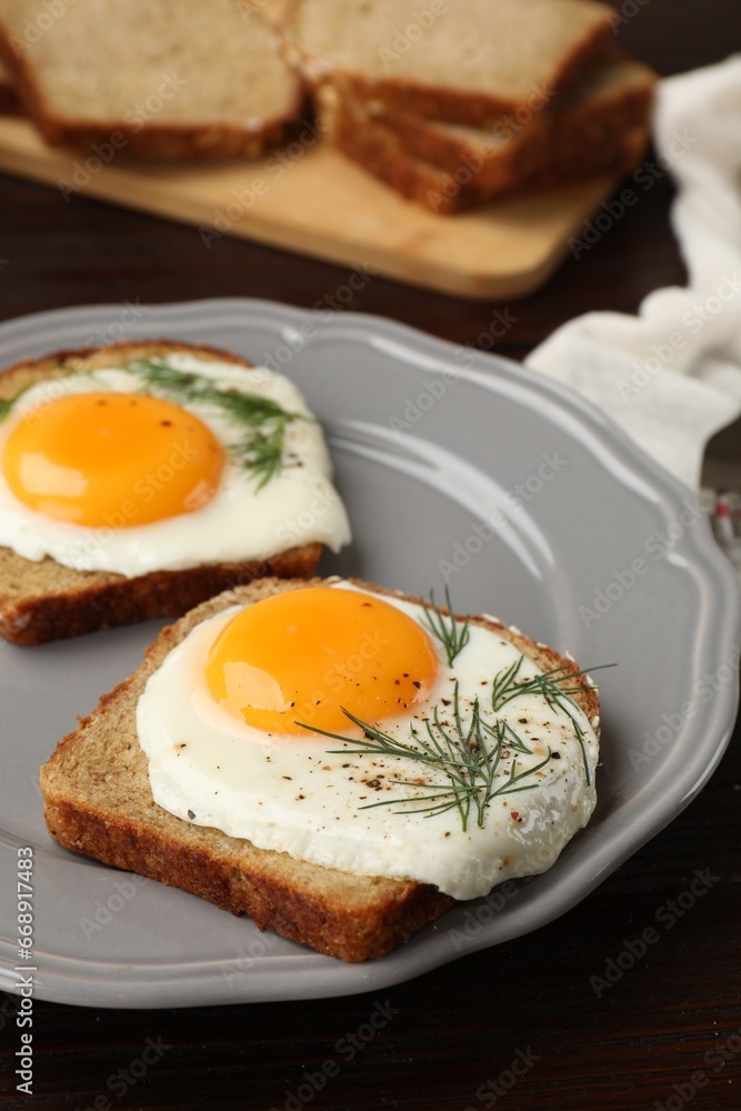Plate with tasty fried eggs, slices of bread and dill on dark wooden table, closeup Plate with tasty fried eggs, slices of bread and dill on dark wooden table, closeup
