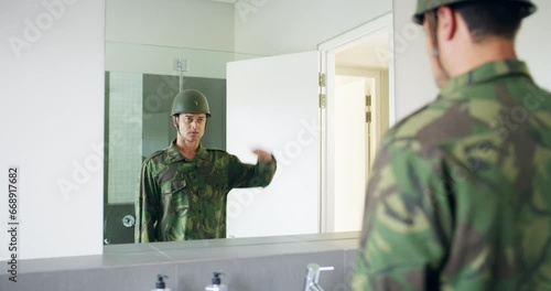 Soldier in bathroom in with mirror, hemet and uniform in camouflage getting ready for bootcamp. Army barracks restroom, battle and military man looking at reflection with courage, loyalty and service photo