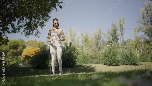young Spanish woman exercising her body with elastic bands in a park in her city