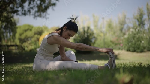 young woman stretching her body in a park on a sunny day