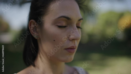 close up of young woman practising breathing exercises in a park