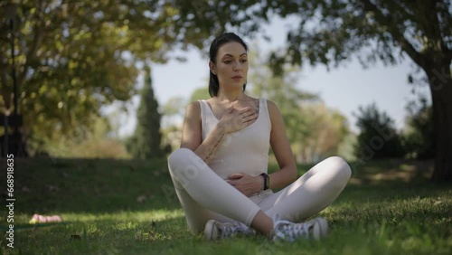 young woman practising breathing exercises in a park