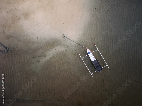 Aerial photo of small traditional fisherman boat at Sanur Beach, Bali, Indonesia. Concept for marine tourism, fishing activity, holiday and exotic asia tropical beach. Empty blank text copy space