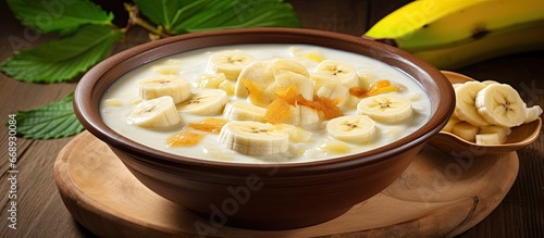 Thai dessert called Kluay Buad Chi Bananas cooked in coconut milk served on a wooden table Focus on the bowl photo