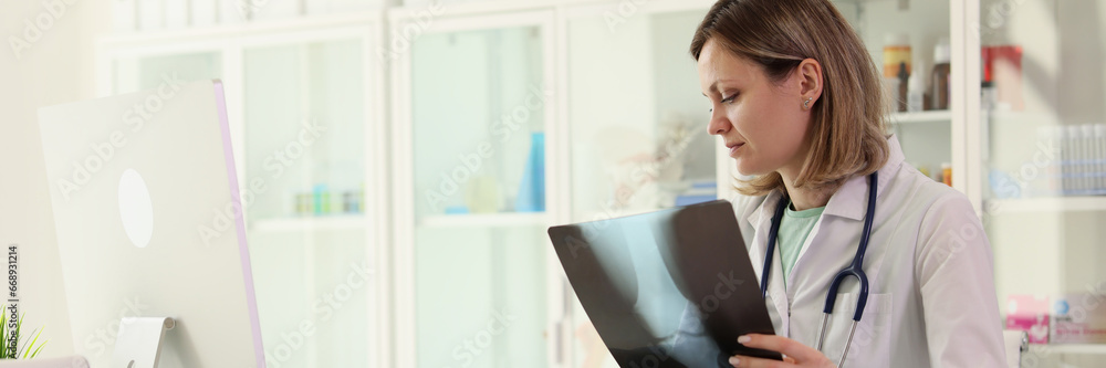Focused doctor examines x-ray of patient joint making notes Focused doctor examines x-ray of patient joint making notes