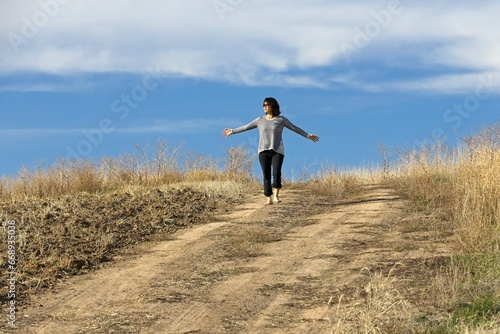 Woman walking barefooted on dirt path.