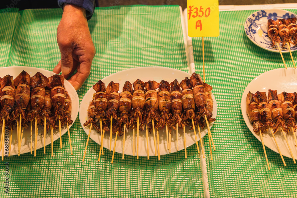 calamari skewers served on plates by a male hand in Tokyo, Japan calamari skewers served on plates by a male hand in Tokyo, Japan