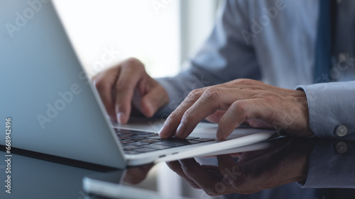 Businessman working on laptop computer at modern office. Business man hands typing on laptop computer keyboard