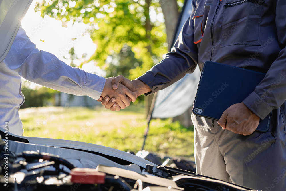 At Auto Service. Cropped view of auto mechanic and customer holding hands, car repair, maintenance, people gesture and concept, mechanic with clipboard and man or owner shaking hands at car shop
