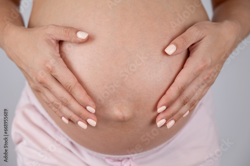 Close-up of pregnant woman's belly in third trimester on white background.  © Михаил Решетников