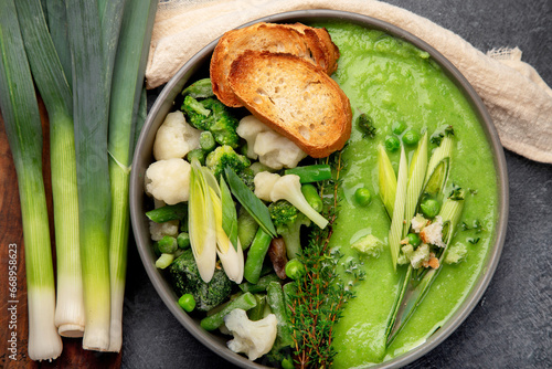 Delicious healthy green cream soup in a bowl with croutons on table.