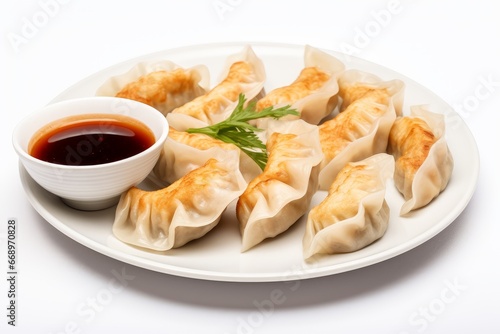 Photo of a plate of Chinese dim sum with dipping sauce on a clean white background. Generative AI © Aditya