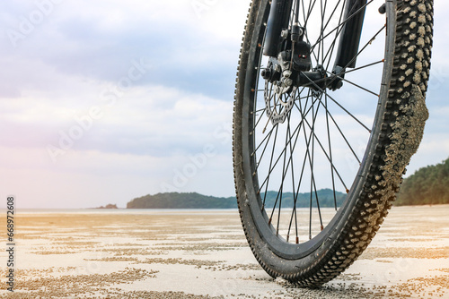 Fototapeta Naklejka Na Ścianę i Meble -  Front wheel of a mountain bike on a sandy beach in Thailand. The concept of cycling in unusual places.