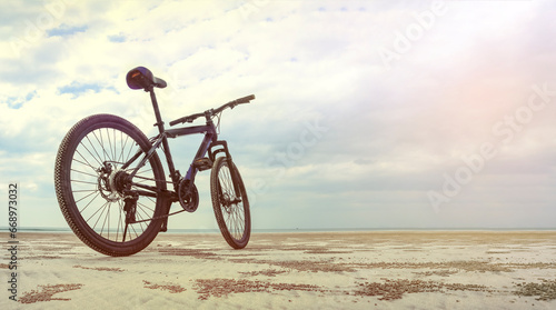 Low angle mountain bike on a sandy beach with the sea in the background. Travel, action, vacation, healthy lifestyle concept.