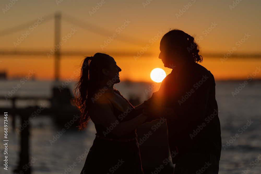 Couple dancing by the sea during golden hour.
