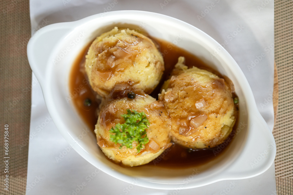 Baked mashed potatoes and gravy sauce which is served in white bowl and placed on table. Italian food object photo, close-up. Baked mashed potatoes and gravy sauce which is served in white bowl and placed on table. Italian food object photo, close-up.