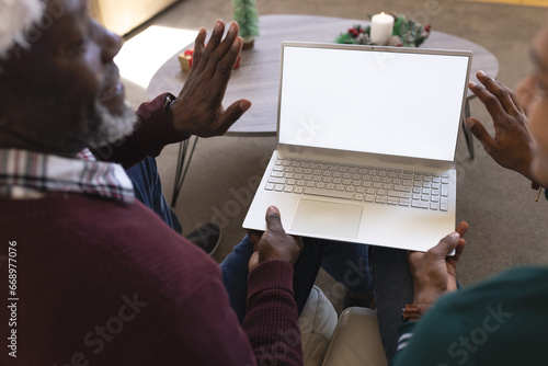 Happy african american father and son having christmas laptop video call, copy space screen