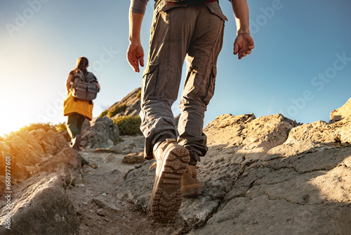 Two young hikers walk with backpacks in mountains at sunset. Close up photo of legs © cppzone