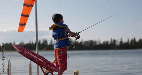 Young boy casts fishing line from cottage dock in summer - summer vacation fun photo