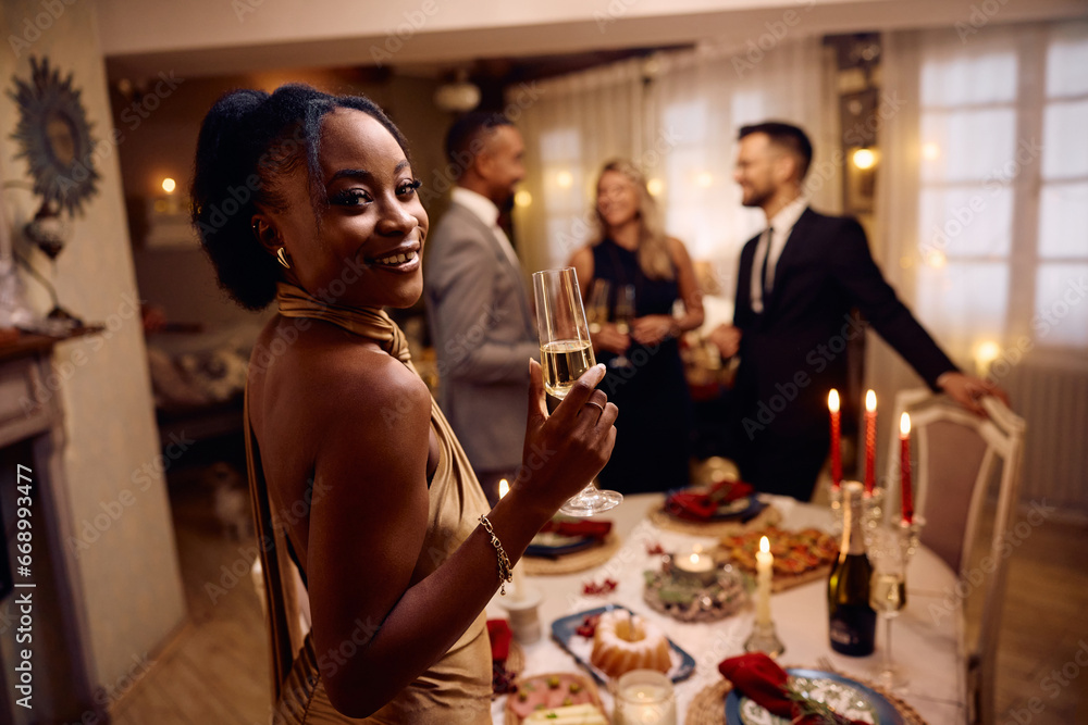 Happy black woman with glass of champagne during Christmas party looking at camera. Happy black woman with glass of champagne during Christmas party looking at camera.