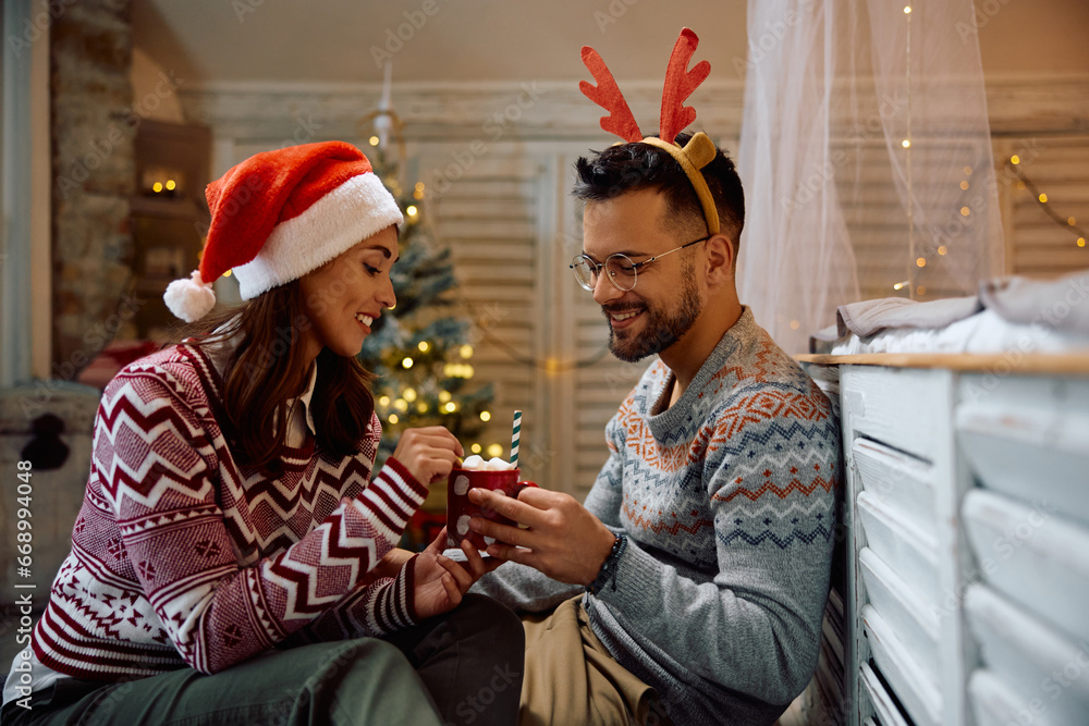Obraz premium Young couple enjoys in cup of hot chocolate with marshmallows during winter holidays at home.