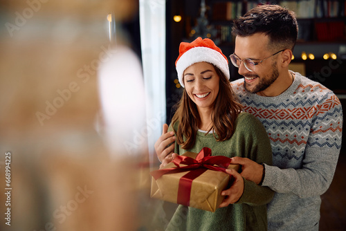Happy woman receives gift box from her boyfriend on Christmas day at home.