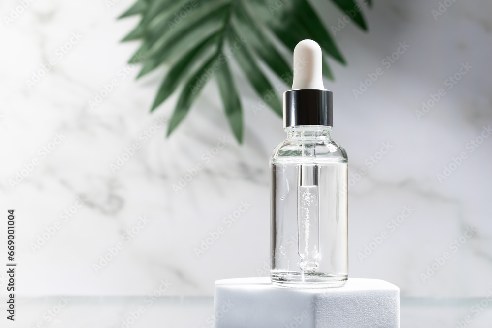 serum in bottle with green leaf on the podium on a marble background serum in bottle with green leaf on the podium on a marble background