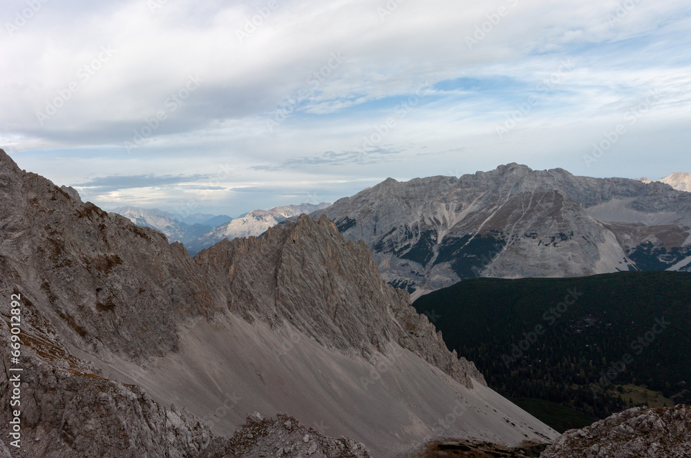 View of the Alps covered by forests and meadows and naked rocky summits. Panorama