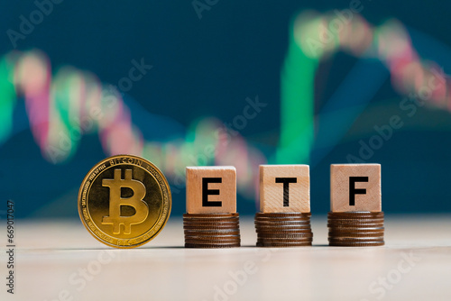Bitcoin gold coin words ETF wooden blocks on rows stack coins and defocused chart background, cryptocurrency bitcoin halving concept. The bitcoin ETF which refers to Exchange Traded Fund. photo