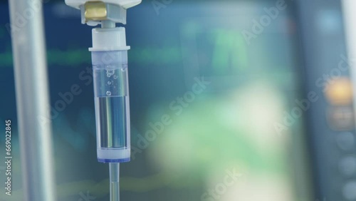 Intravenous drip on the background of a heart rate monitor. The surgeon performs an operation. Modern medicine.