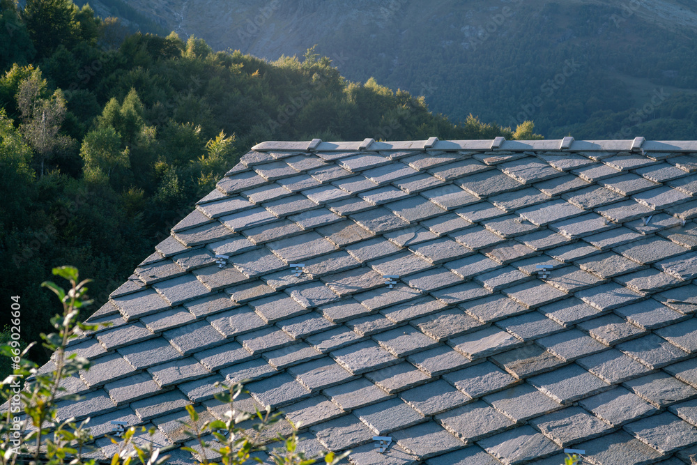 roof with stone tiles, typical of mountain house houses, blue gray granite stones, mountains in background. thermal insulation, energy class.